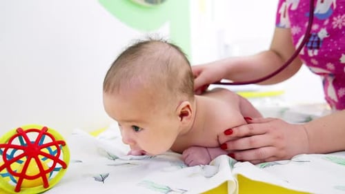Doctor Examines Cute Baby on Hospital Bed
