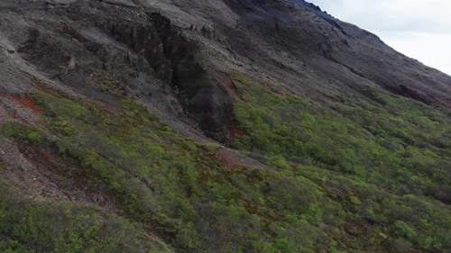 Luftbild, das einen Höhleneingang zu einem majestätischen Berg im isländischen Hochland zeigt.