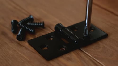 Close up of screws screwed into wood with a screwdriver.