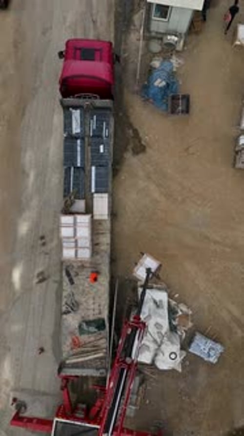 Vertical Video Above the Construction Zone Aerial Perspective of Crane Unloading Cargo with Busy