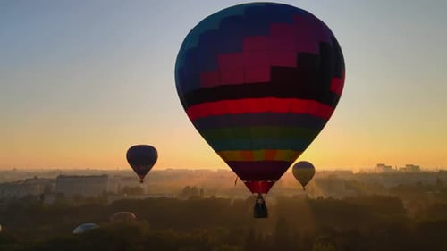 Colorful Hot Air Balloons Floating Above a City at Sunset