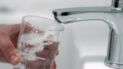 Water Being Poured into Glass at the Sink