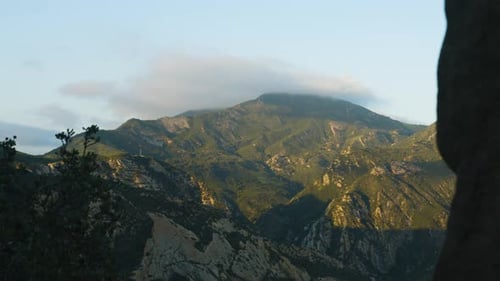 Sunset overlooking a mountain as clouds pass with shadows moving up the slope (4k)
