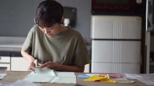 Woman Cutting Fabric with Scissors at Table