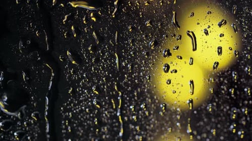 Rain Drops on Glass Reflecting City Lights