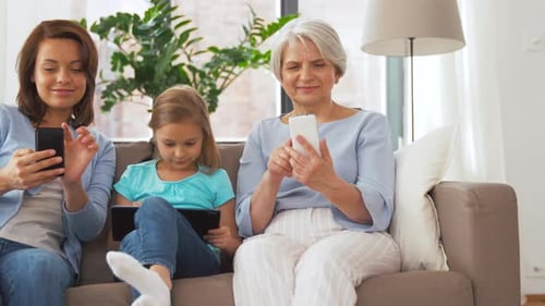 Three Females Sitting on Couch Using Devices