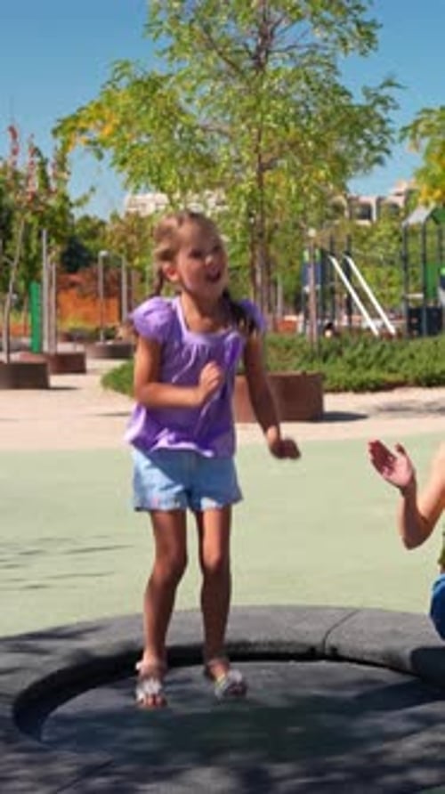 Happy Energetic Girl Jumping on Trampoline in Playground