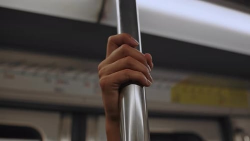 Close up of female hand holding grab bar inside moving subway wagon. Real time