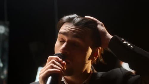 Man Singing Passionately into Microphone on Stage