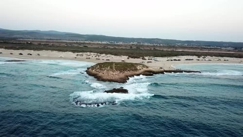 Secluded coastline of sand and isolated small island of rock. Aerial