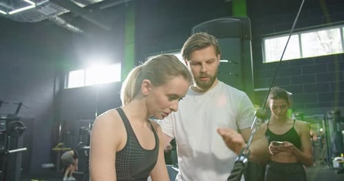 Trainer Support Athlete Woman Doing Push Ups with Trx Fitness Straps in the Gym While Join Lessons