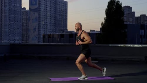 Muscular Man Doing Lunges on Rooftop at Dawn