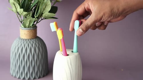 Hand picking up colorful toothbrush close up