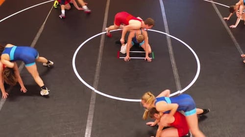 Coed group of wrestlers doing a spin drill during wrestling practice.