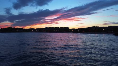 Colorful sunset over Playa de l'Arrabasada in Tarragona with ocean waves and silhouettes in the dist
