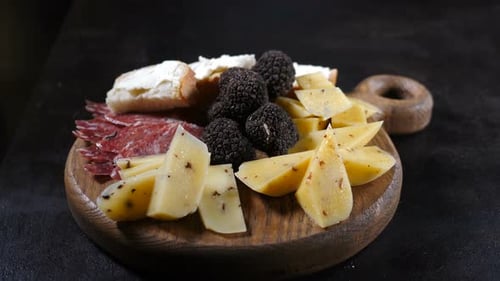 Serving Board Displaying Sliced Cheese, Salami, and Truffles