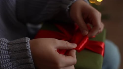 Tying Red Ribbon on Christmas Gift Close Up