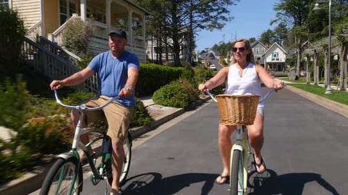 Couple Riding Bicycles Together In Coastal Vacation Community