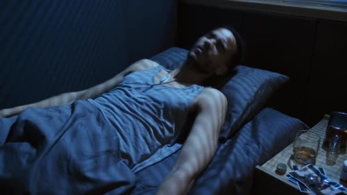 High angle view close-up of young Black military man lying on bed having panic attack after nightmar