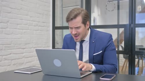 Frustrated Businessman Working on Laptop in Office