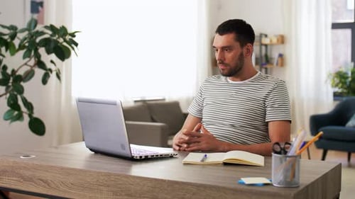 Man Attending Video Conference on Laptop at Home