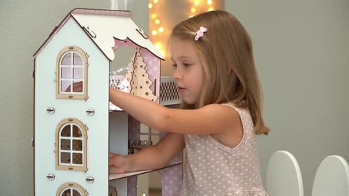 Girl Playing with Three-Story Dollhouse in a Home