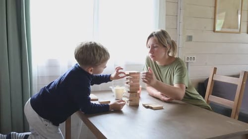 Mother and Son Play Jenga Board Game in Home