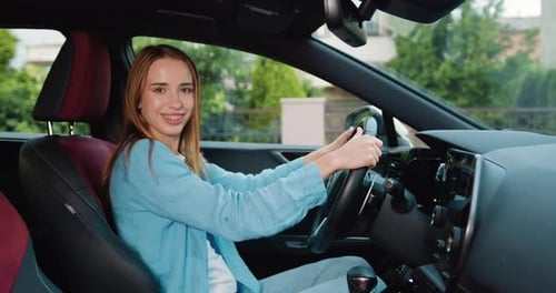 Young Woman Smiling in Car, Holding Steering Wheel