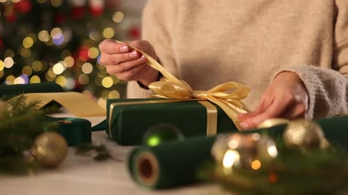 Woman Tying Bow on Green Christmas Gift