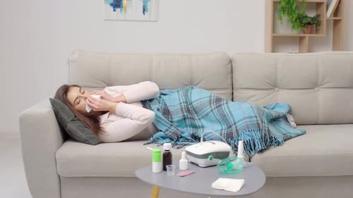 Young Woman Sick on Couch Uses Tissue