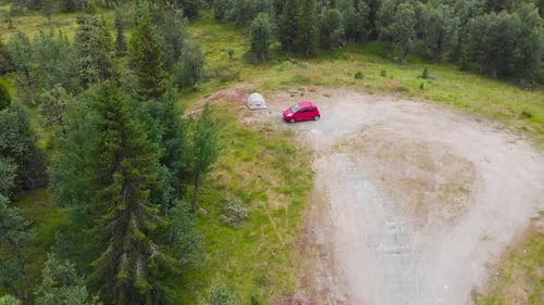 Red Car And A Tent In A Camping Ground With Vegetation In Sweden. aerial drone