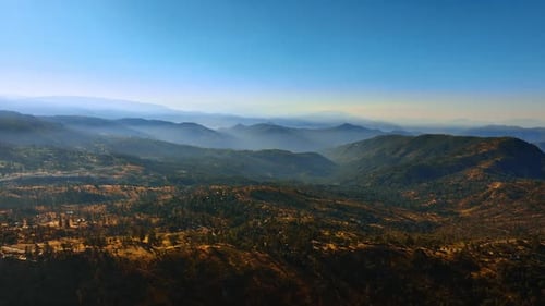 Flying above the mountainous landscape at sunset. Beautiful scenery of rocks with greenery of woods