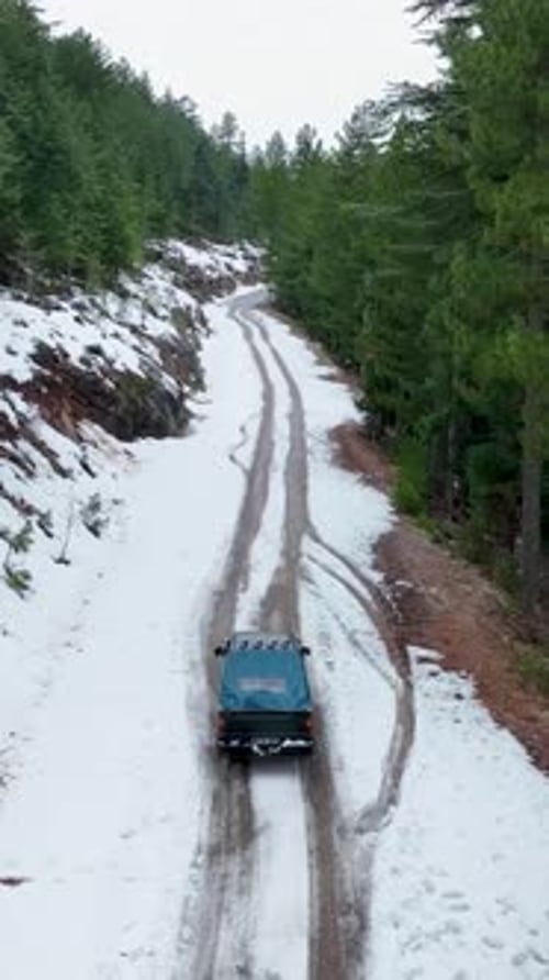 Vertical Video Above the Winter Trail Aerial Cinematics of Pickup Truck on Snowy Road in Green