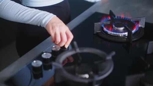 Female Hand Turns on Kitchen Cooktop Gas Burner and Natural Gas Ignites Burns with Blue Flame Human