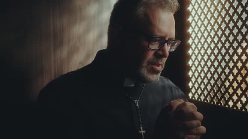 Priest Saying Prayer of Absolution in Confessional Booth
