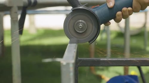 workman professional specialist . A man grinding a piece of square tubing forming part of a table
