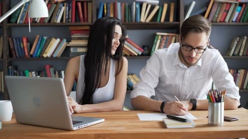 Two Students Brainstorm Work By Discuss With Pc In Hipster Loft Closeup With Background Books. Hi...