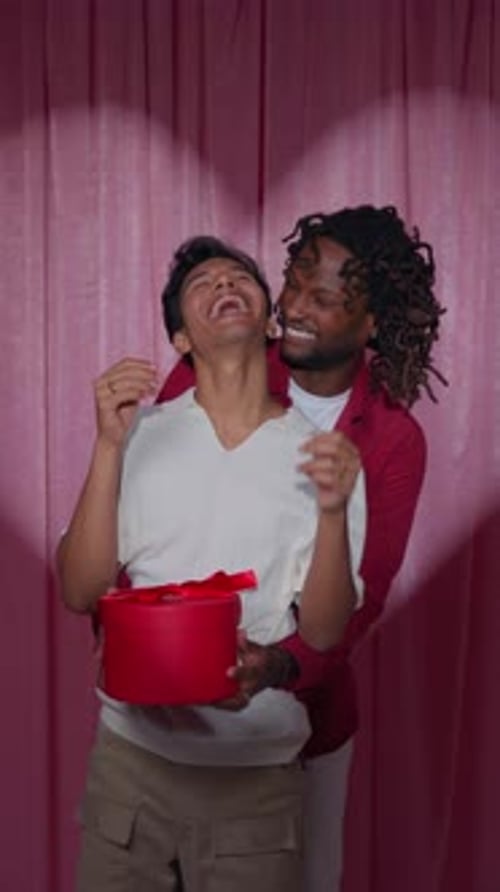 Affectionate Male Couple With Surprise Valentine Gift Box in Photo Booth