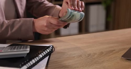 Woman Counting Stack of Cash at Desk