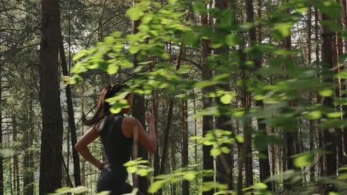 Joven atleta femenina corriendo en el bosque