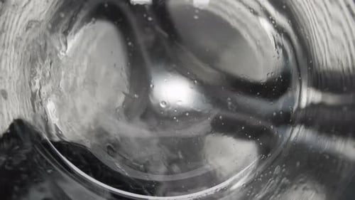 Waschen in der Waschmaschine: Trommel mit Schaum und Wasser dreht das Waschen der Kleidung