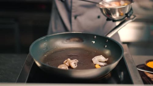 Professional kitchen in the restaurant of the hotel the chef lays out seafood with tongs on a pan