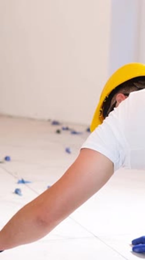 Construction Worker Installs White Tiles Indoors