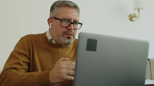 Mid-Aged Businessman Web Conferencing on Laptop in Office