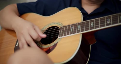 Person Playing Acoustic Guitar Indoors