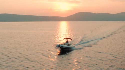 Aerial view of a woman driving speed boat. A drone flies around the boat — beautiful nature.