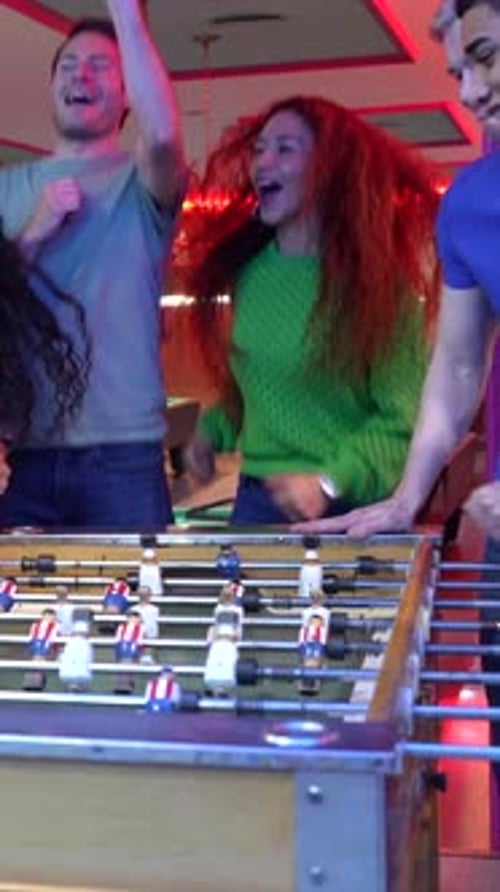 Friends Celebrating Victory Playing Table Football in Bowling Alley
