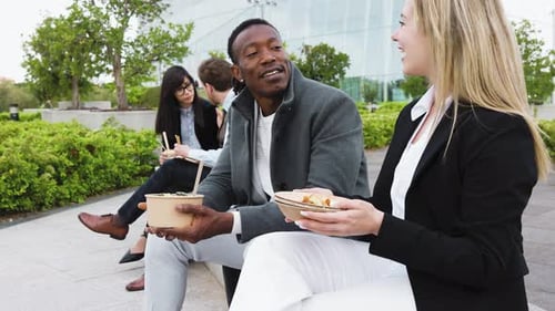Happy multiracial business people having a lunch break outside office