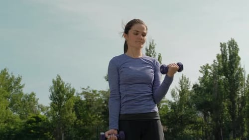 Woman Doing Bicep Curls in Urban Park