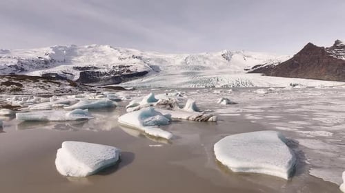 Drone pullback over icy Fjallsárlón glacier lagoon - scenic Iceland winter landscape